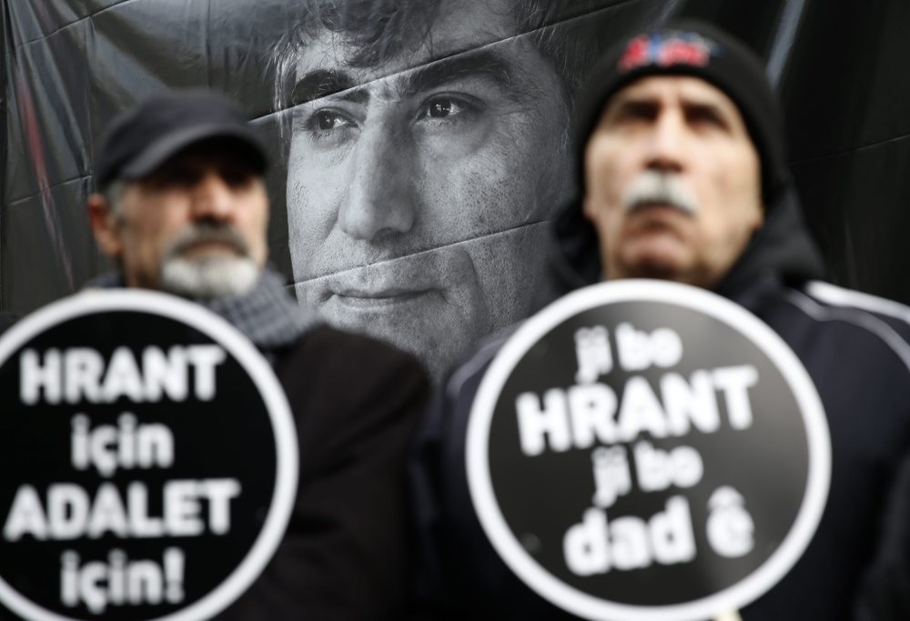 Activists hold placards reading ,For Hrant, For Justice, against the backdrop of a large poster of the slain journalist during a commemoration ceremony in January 2016 in Istanbul.