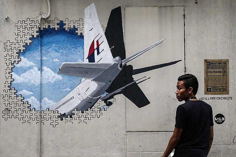  A file picture dated 06 March 2015 shows a man in front of a Malaysia Airlines flight MH370 mural painting at Shah Alam, outside Kuala Lumpur, Malaysia. (EPA Photo)