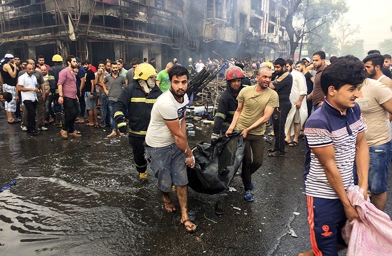 In this Sunday July 3, 2016, file photo, Iraqi firefighters and civilians carry bodies of victims killed in a truck bomb at a commercial area in Karada neighborhood, Baghdad (AP Photo)
