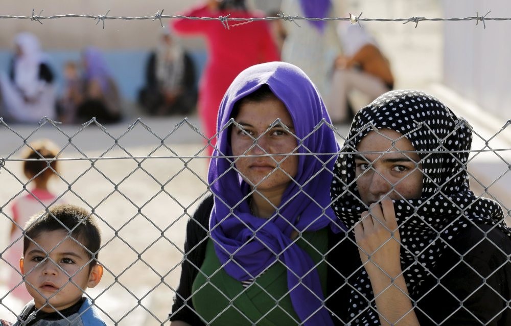 Refugees stand behind fences at a Syrian and Iraqi refugee camp in the southern Turkish town of Midyat in Mardin province, June 20, 2015.