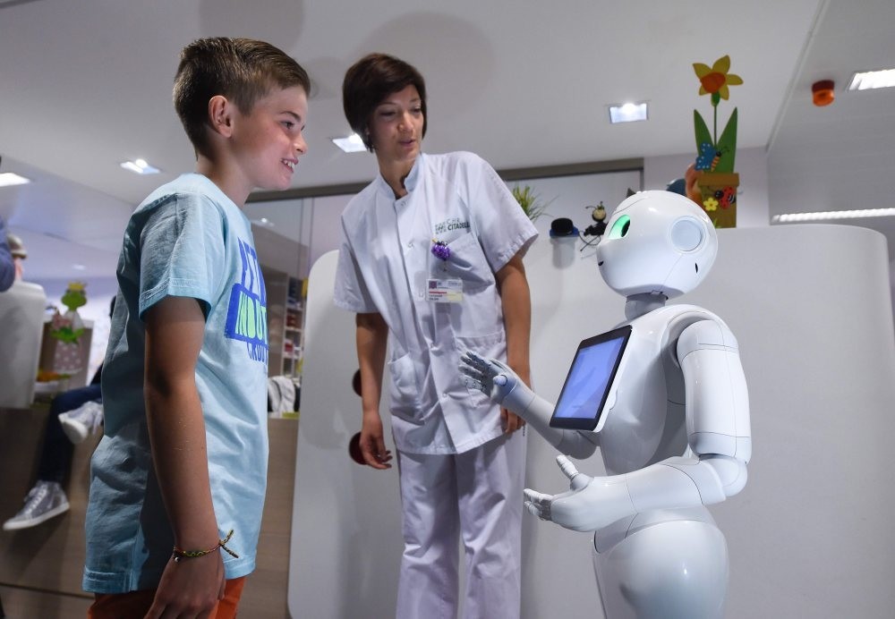 A young boy talks with the robot Pepper next to a nurse at the CHR Citadel hospital centers of Liege.