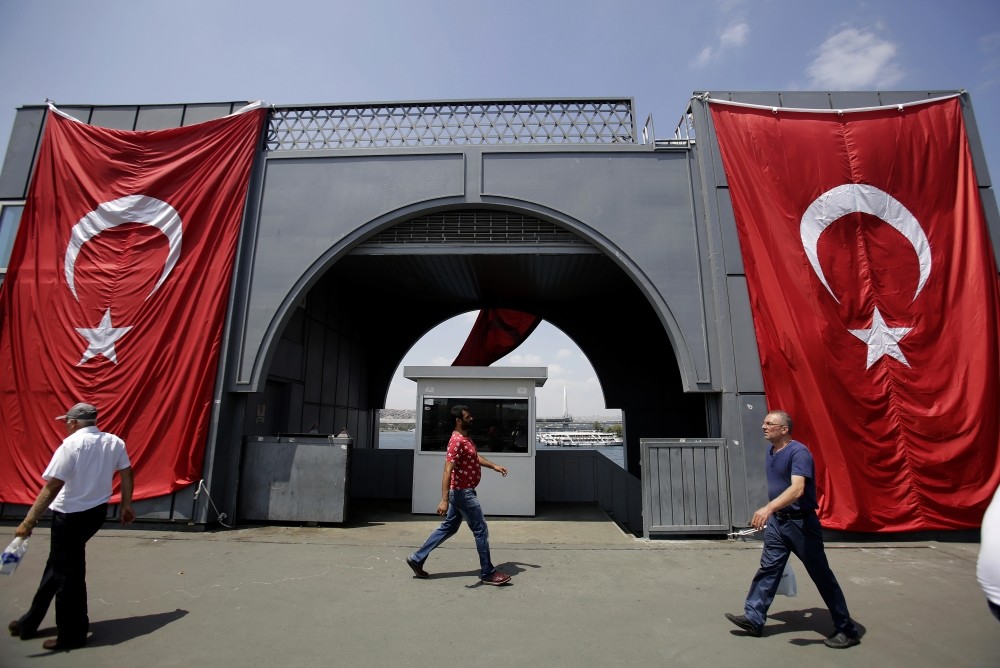 Men walking Galata Bridge where Turkish flag is displayed to protest the Gu00fclenists' failed coup attempt, Istanbul, Aug. 2.