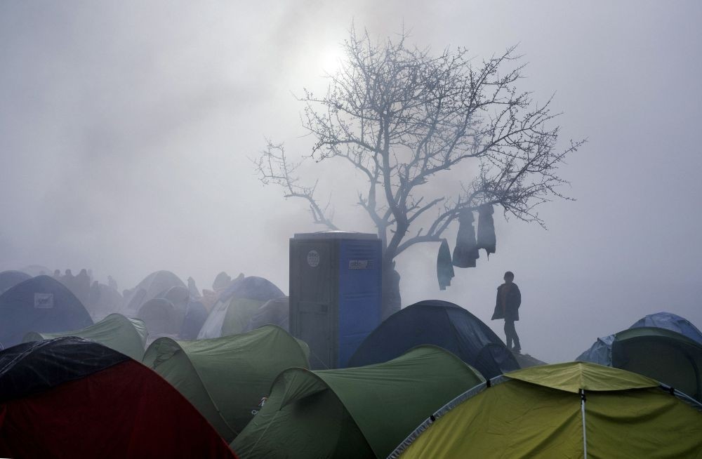 A boy standing among tents during a foggy morning at a makeshift camp at the Greek-Macedonian border near the Greek village of Idomeni on March 8, 2016.