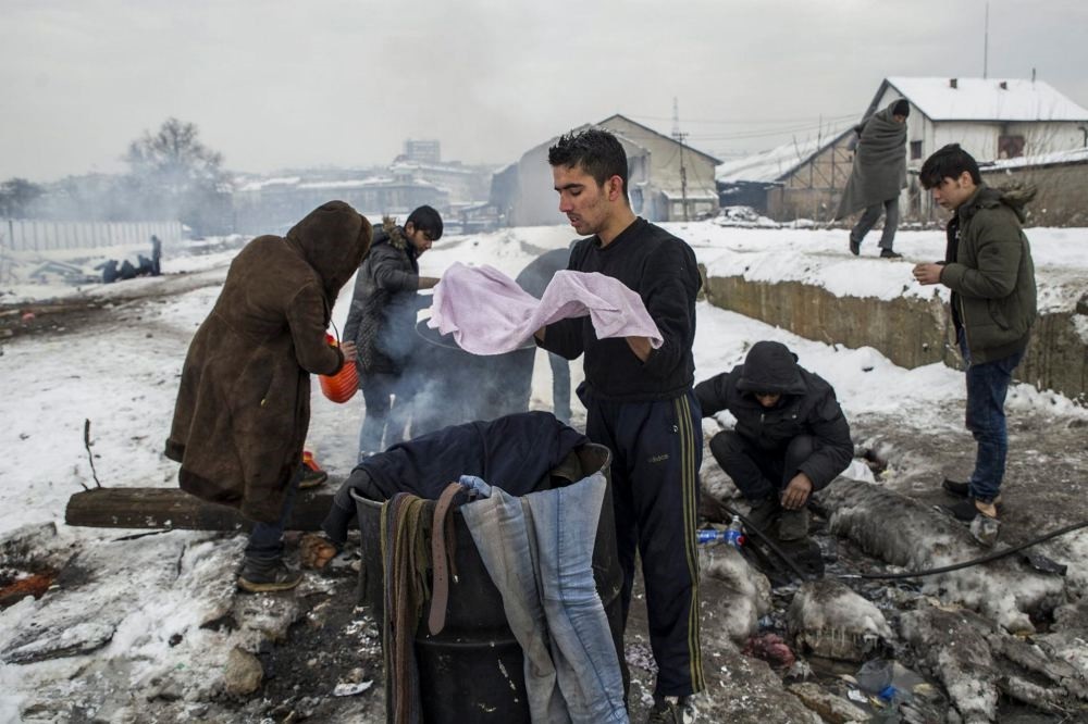 Refugees wash their clothes as they take a shower outside a derelict warehouse where they have taken shelter in Belgrade, Serbia on Jan. 12.