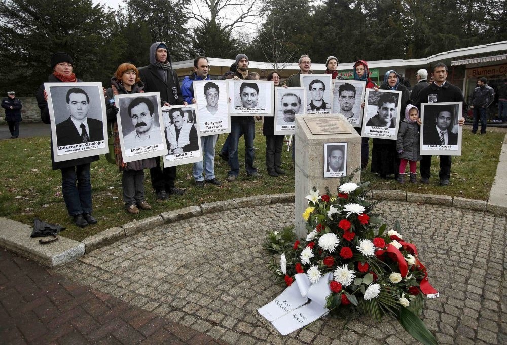 People carrying photos of NSU victims stand around a monument erected in memory of Halit Yozgat, one of the victims, in Germany's Kassel. Amnesty says ,institutional racism, led police to downplay racist motives behind the murders.