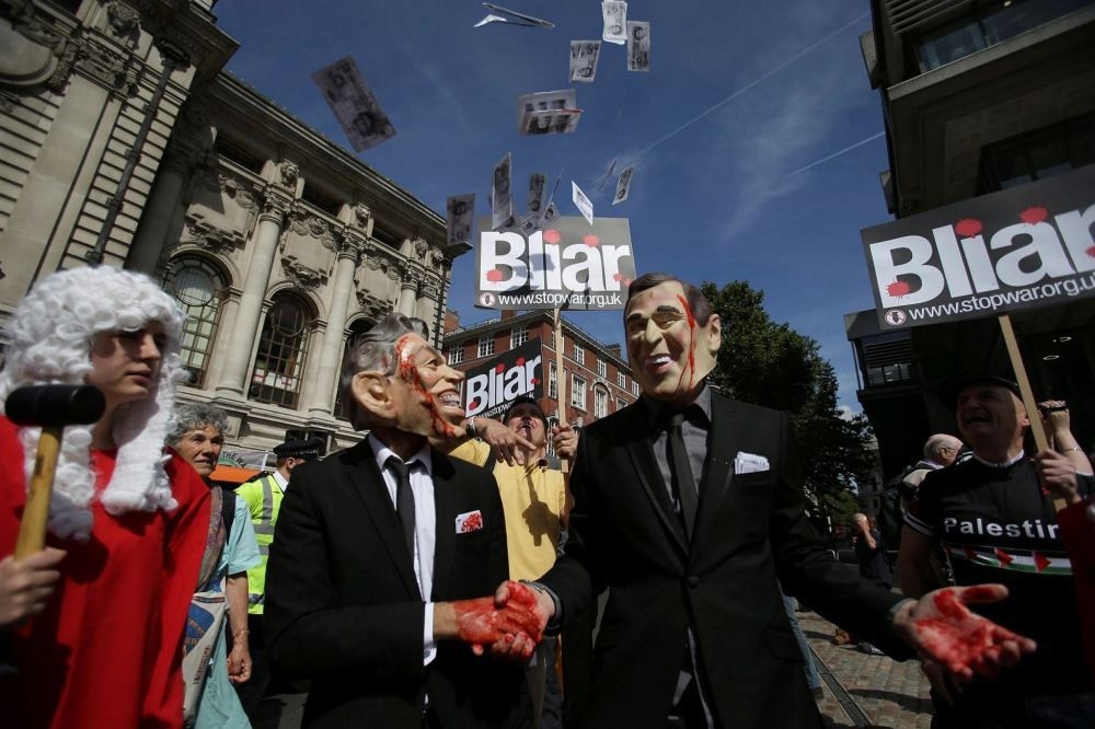 Demonstrators wearing masks depicting former British Prime Minister Tony Blair (L) and former U.S. President George W. Bush protest in Central London.