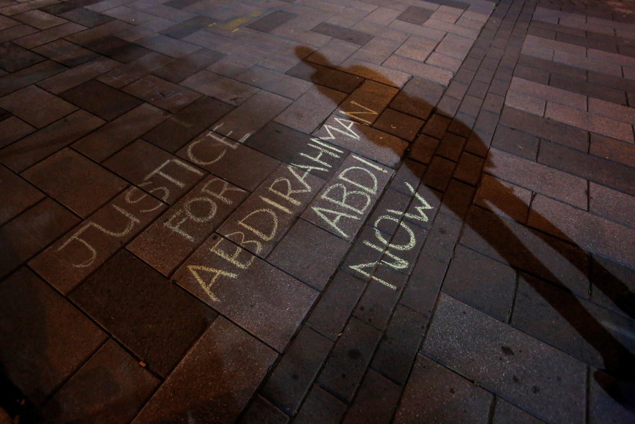 A man casts a shadow near a message written in chalk during a vigil for Abdirahman Abdi, a Somali immigrant to Canada who died after being hospitalized in critical condition. (REUTERS Photo)