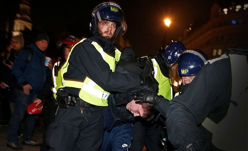 Police officers apprehend a protester during the ,Million Mask March, in London. (Reuters Photo)
