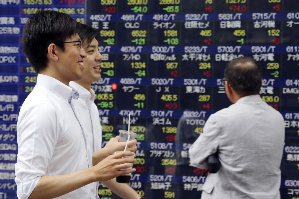 People walk by an electronic stock board of a securities firm in Tokyo, Friday, on July 15. Asian shares were higher Friday after China reported steady economic growth in the second quarter of the year.