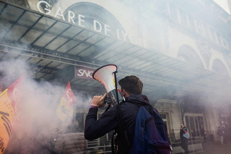 A protester holds a megaphone next to burning flares outside the Gare de Lyon in Paris on April 26, 2016, during a demonstration by railway workers of French state rail operator SNCF, as part of a strike to defend their work conditions. (AFP Photo)