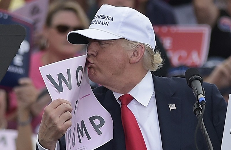 Republican presidential nominee Donald Trump kisses a ,Women for Trump, placard during a rally at the Lakeland Linder Regional Airport in Lakeland, Florida on October 12, 201 (AFP Photo)