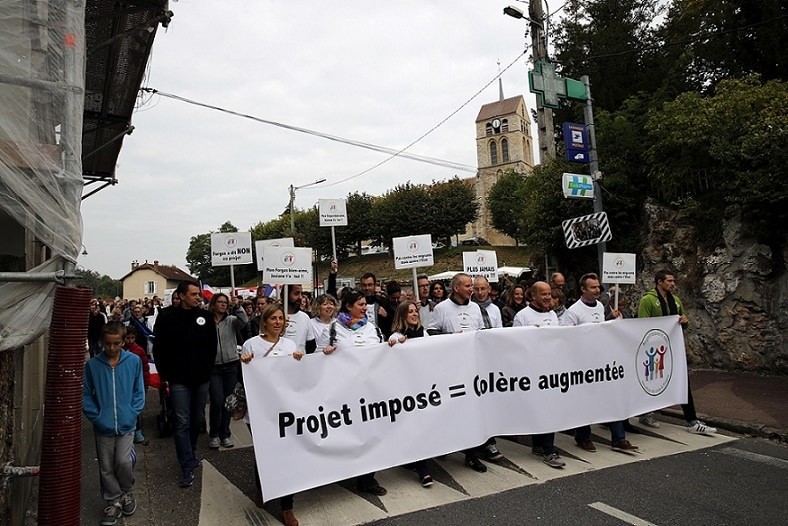 Local residents hold boards reading: ,Not Against Migrants, but Against the State, during a march against French governmentu2019s refugee policy in Forges-les-Bains, south of Paris, Oct. 8, 2016. (AP Photo)