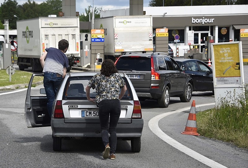 People push their car to save oil before refueling at a gas station following the blockades of oil depot (AFP photo)