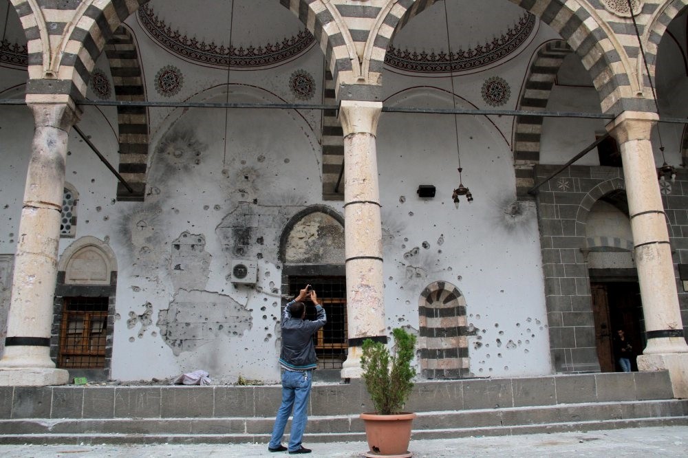 A man takes pictures of the damaged walls of a mosque in the Sur district of Turkeyu2019s southeastern Diyarbaku0131r province, Oct. 13, 2015.