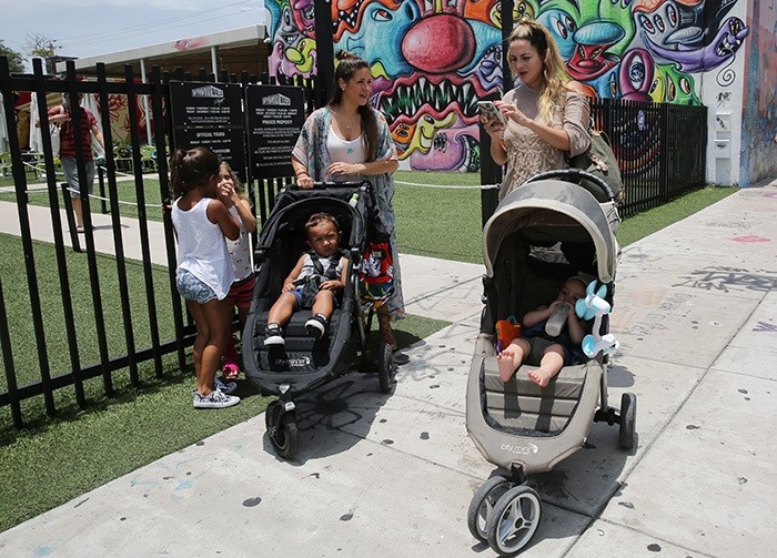Vanessa Gomez, 33, left, with her son Ezra, 2, and her friend Cristy Fernandez, 33, with her 9-month-old- son River, of Miami, walk in the Wynwood neighborhood of Miami, Friday, July 29, 2016. (AP Photo)
