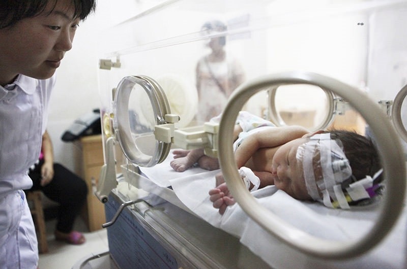 A nurse (L) looks at a newborn baby resting in an incubator. (Reuters File Photo)