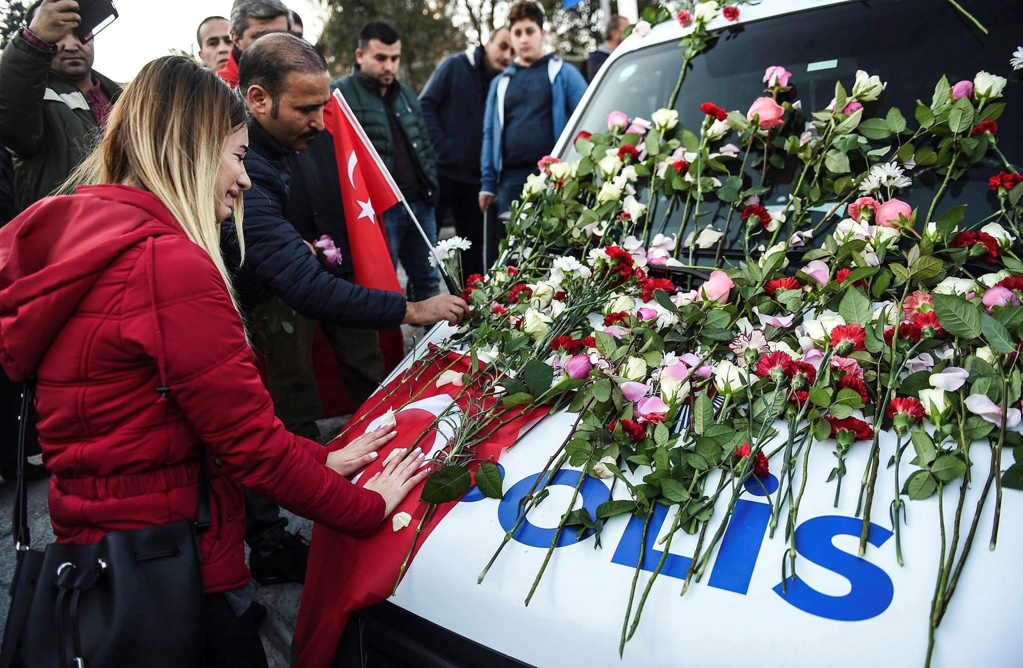 A woman cries next to a police car at the scene of the attack covered with flowers left by mourners. The public marched on Sunday against terror and to remember the victims.