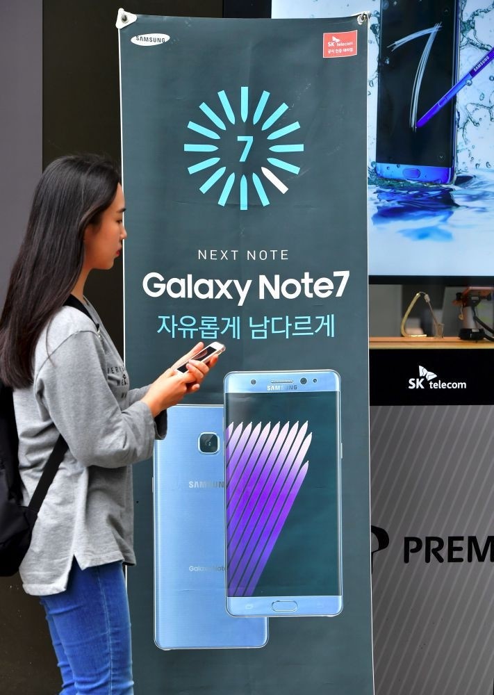 A woman walks past billboards of Samsung Galaxy Note 7 at a mobile phone shop in Seoul.