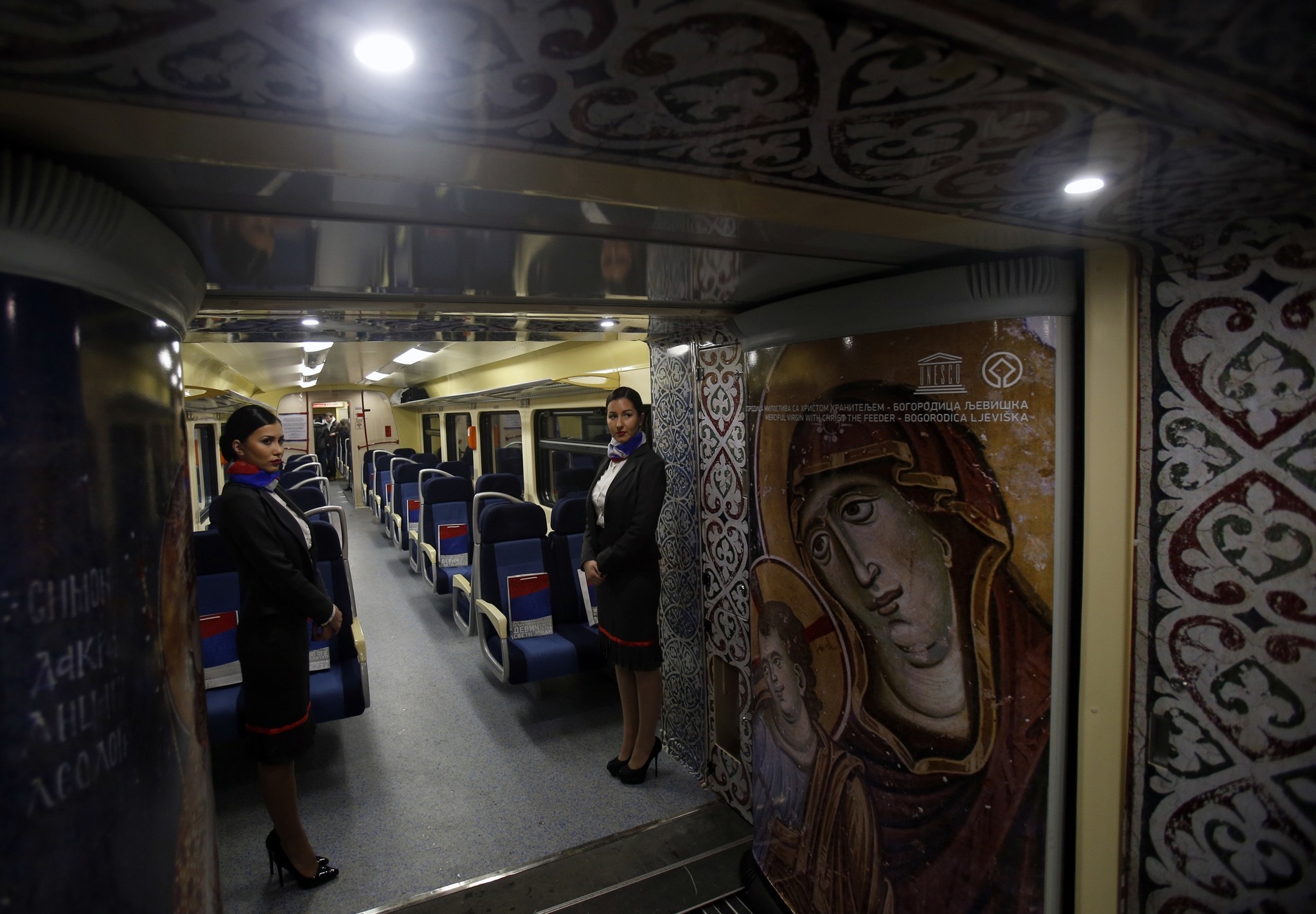 Train hostesses stand in a train carriage decorated with iconic religious figures as it departs from Belgrade to Mitrovica, Kosovo at Belgrade's railway station, Serbia, Saturday, Jan. 14, 2017. (AP Photo)