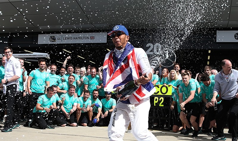 Mercedes driver Lewis Hamilton of Britain celebrates spraying champagne in team garage after winning the British Formula One Grand Prix at the Silverstone racetrack. (AP Photo)
