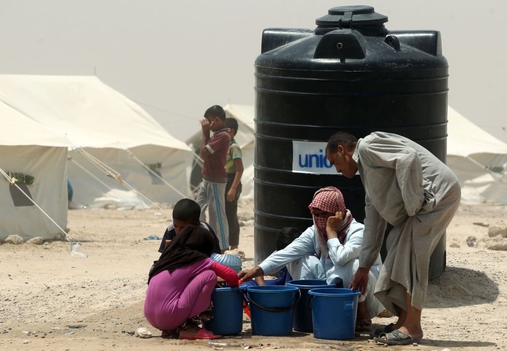 Iraqis displaced from Fallujah gather next to a water tank at a newly opened camp where they are taking shelter in Amriyat al-Fallujah, June 27.