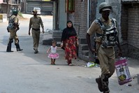 Indian paramilitary troopers patrol as a Kashmiri woman with a child walks during a curfew in Srinagar on August 5, 2016. (AFP Photo)