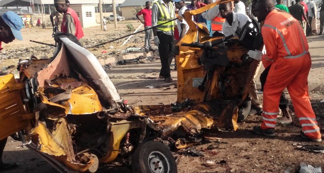This file photo taken on October 29, 2016 shows emergency personnel standing near the wreacked remains of a vehicle ripped apart following two suicide bombings in Nigeria. (AFP Photo)