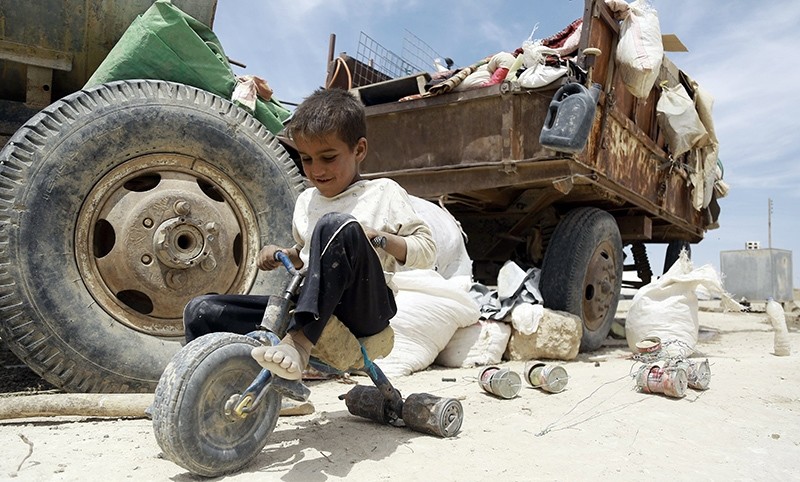An Iraqi child who fled with his family the northern province of Nineveh following the advance of Daesh, plays with a makeshift tricycle in a refugee camp in al-Hawl (AFP Photo)