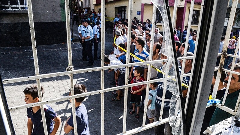 People stand near the explosion scene behind police cordon following a late night Daesh terrorist attack on a wedding party that left at least 50 dead in Gaziantep in southeastern Turkey (AFP Photo)