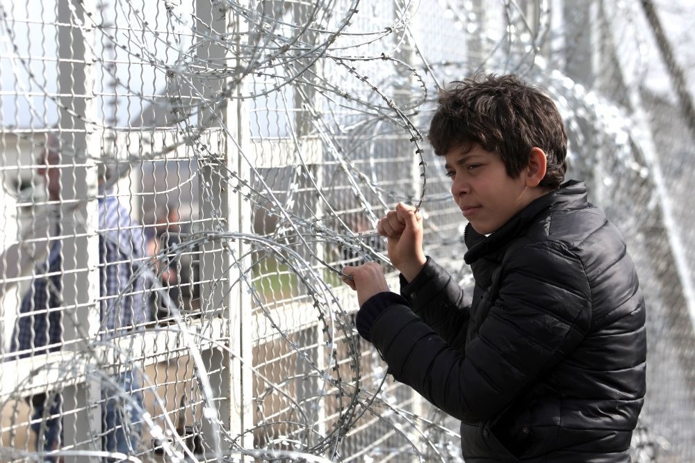 A boy looks through barbed wire as migrants wait to cross the Greek-Macedonian border near the village of Idomeni, March 1. (AFP Photo)