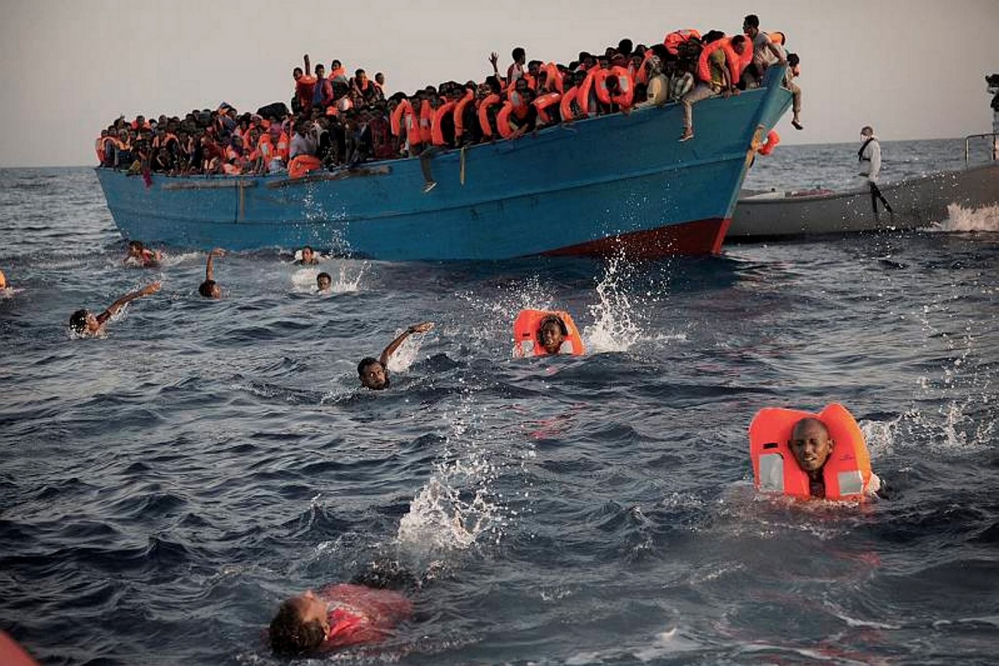 Migrants, most of them from Eritrea, jump into the water from a crowded wooden boat as they are helped by members of an NGO during a rescue operation at the Mediterranean sea. 