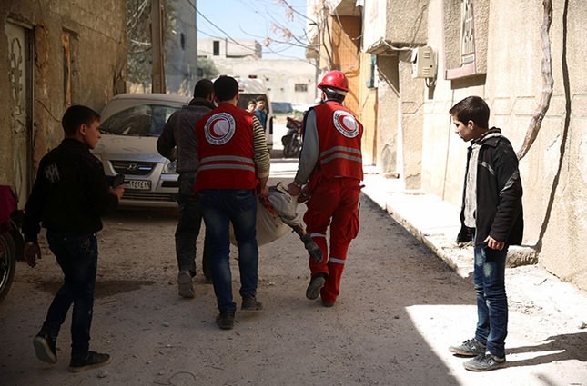 Members of the Syrian Arab Red Crescent carry a body reportedly killed following a Regime airstrike during ceasefire in the rebel-held city of Douma, on February 26, 2016 (AFP Photo)