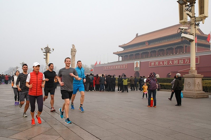 This handout picture taken and provided by Facebook on March 18, 2016, shows Facebook CEO Mark Zuckerberg (front R, grey shirt) running past Tiananmen Gate, the entrance to the Forbidden City, in Beijing. (AFP Photo)