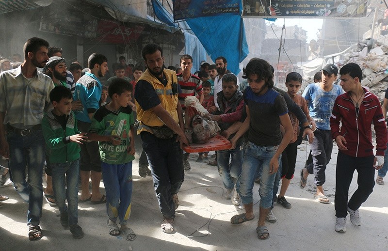 Syrians carry the body of a man following air strikes on the rebel-held Fardous neighbourhood of the northern embattled Syrian city of Aleppo on October 12, 2016