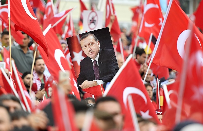 A picture of President Erdou011fan is framed by national flags during a demonstration in Cologne, Germany (AP Photo)