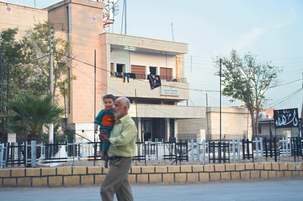 A local carrying his child walking in the main square in the northern Syrian town of Jarablus. Daily Sabah observed the new life in the war-torn town.
