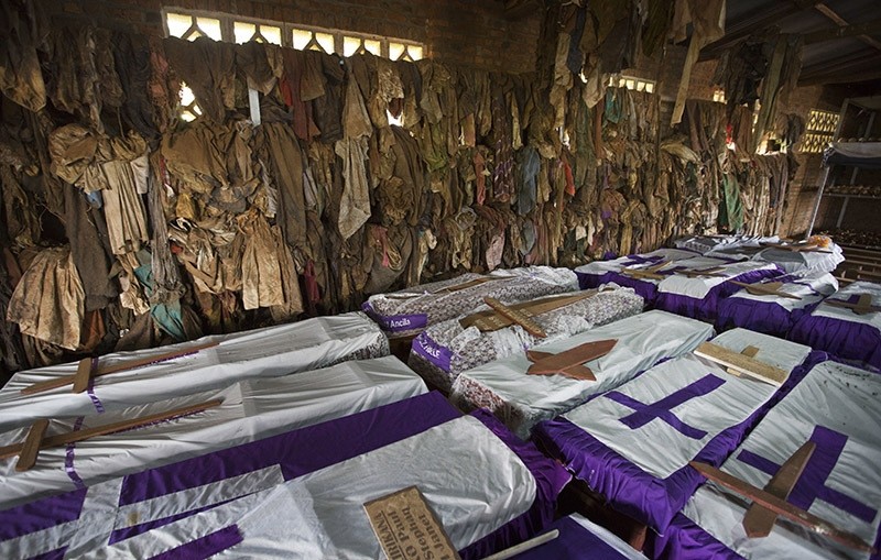 Clothes of some people slaughtered whilst seeking refuge inside the church hang above coffins containing the remains of victims killed in and around the Catholic church during the 1994 genocide in Ntarama, Rwanda. April 2014. (AP Photo)