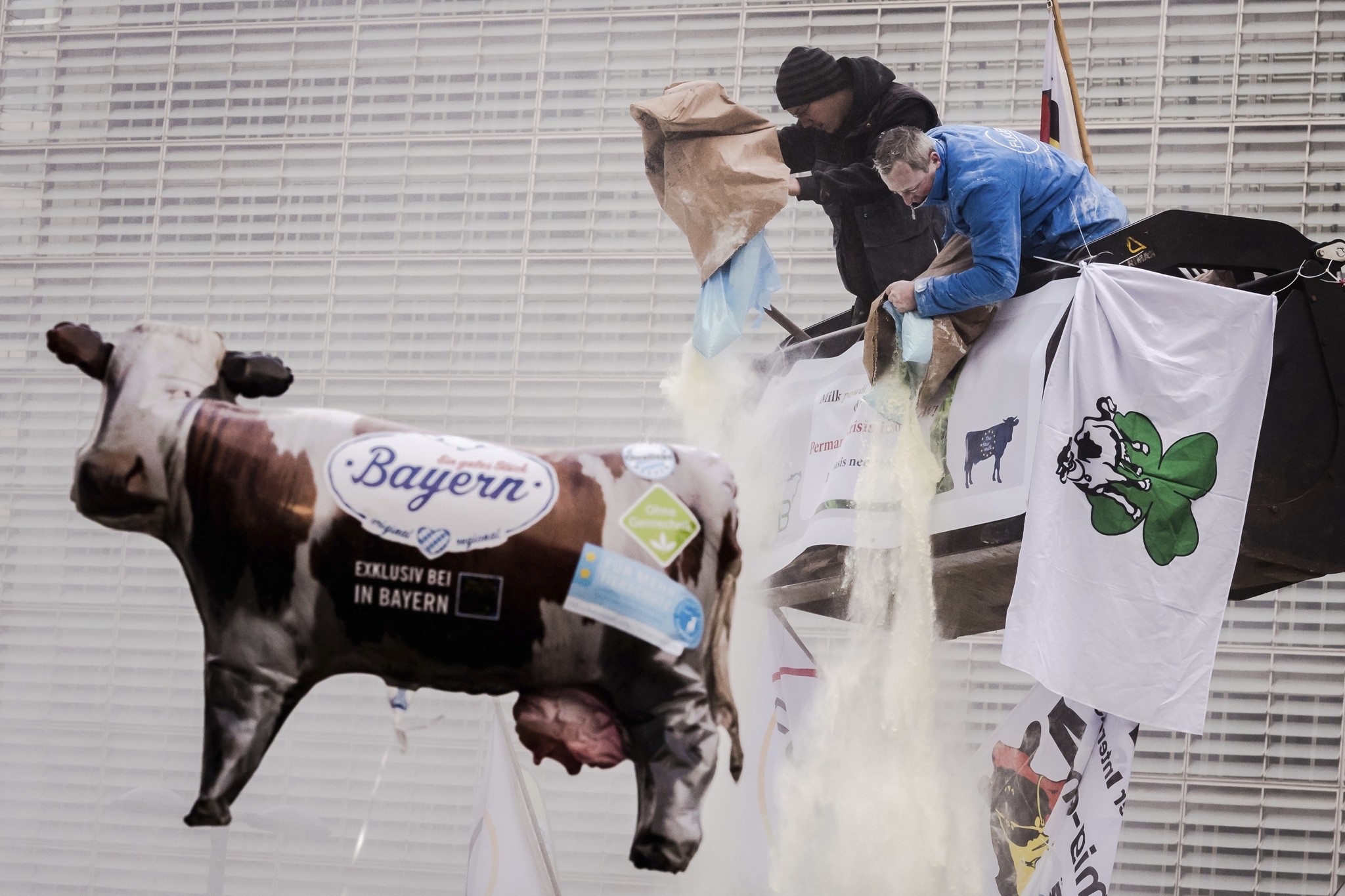 European dairy farmers spray the EU Council building with milk powder to protest the crisis in their sector, in Brussels on Monday, Jan. 23, 2017. (AP Photo)