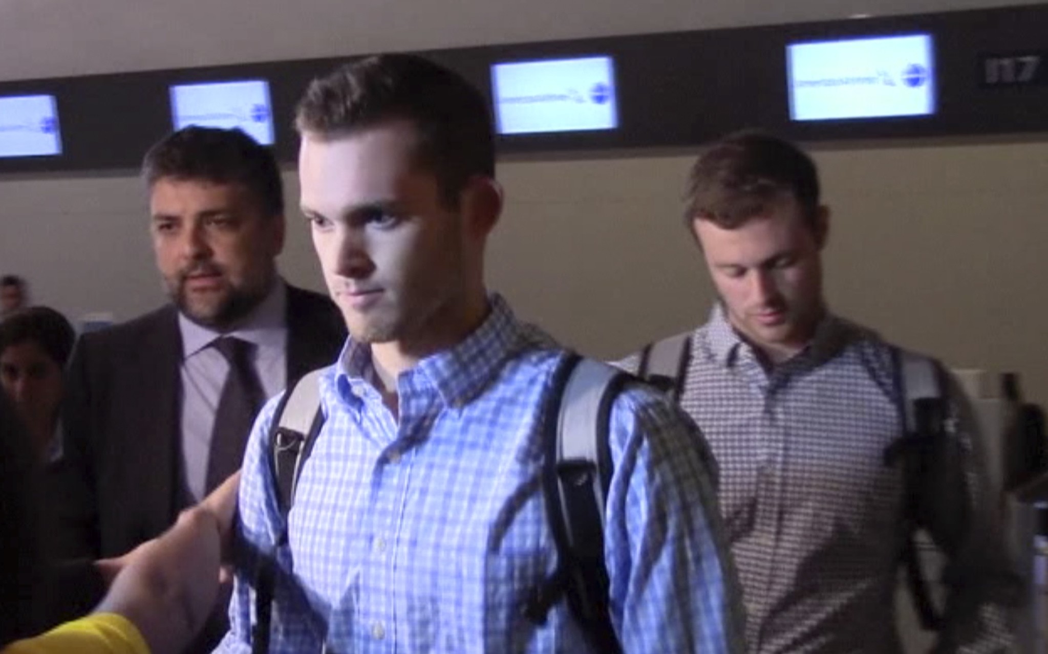 In this image made from video, American Olympic swimmers Gunnar Bentz and Jack Conger walk in the departure area after checking into their flight at the airport in Rio de Janeiro. (AP Photo)