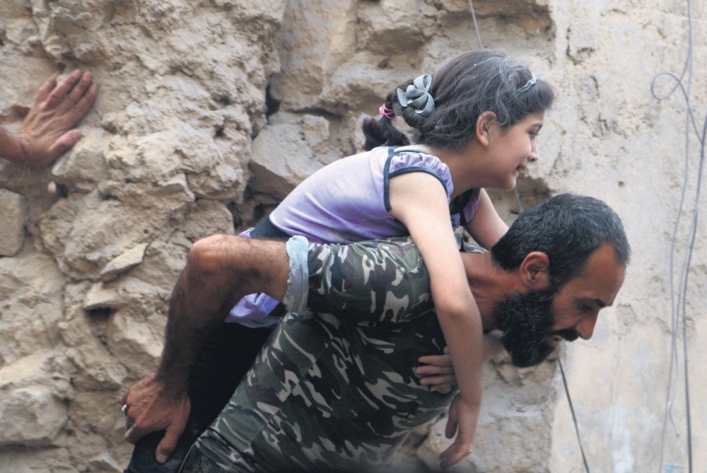 A man carries an injured girl after an airstrike on Aleppo's opposition held Kadi Askar in Aleppo.