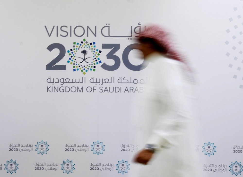 A Saudi man walks past the Vision 2030 logo after a news conference in Jeddah, Saudi Arabia.