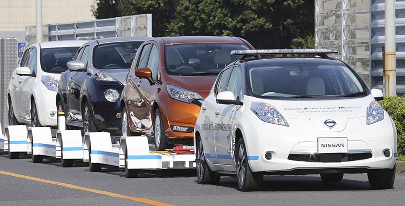 Nissan Motor Co.'S ,Leaf,, with no one inside, pulls a trailer with three other Leafs on it, during a demonstration of the automaker's Intelligent Vehicle Towing system at Nissan Oppama plant in Yokohama, Dec. 5, 2016. (AP Photo)