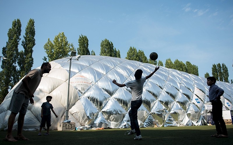 Migrant boys play soccer in front of an emergency accommodation shelter in a big air-inflated tent for asylum applicants in Berlin, Germany (Reuters Photo)