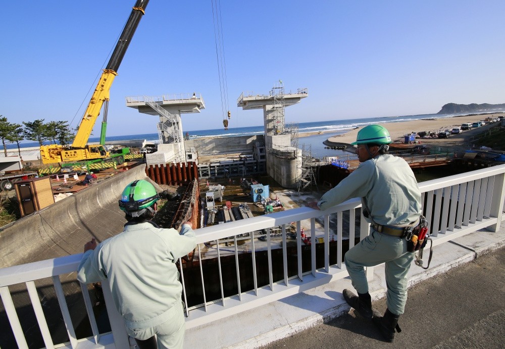 Workers look at a floodgate under construction after a tsunami warning was lifted, in Iwaki, Fukushima prefecture.