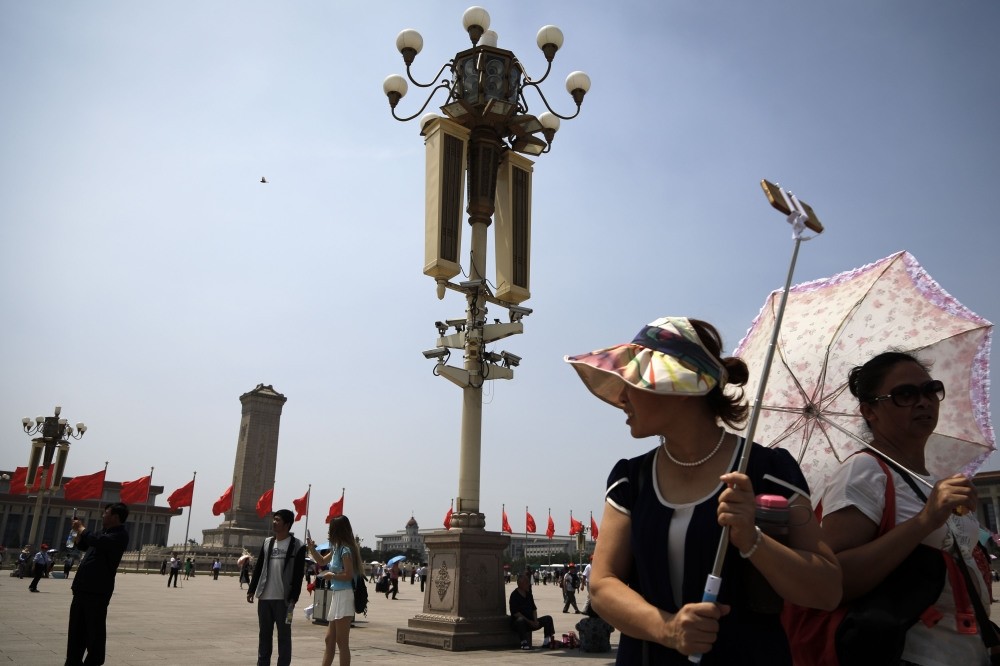Tourists gather near a pole with security cameras attached to monitor Tiananmen Square in Beijing. Chinese authorities are maintaining a tight security around Tiananmen Square ahead of anniversary of deadly 1989 crackdown on pro-democracy protesters.