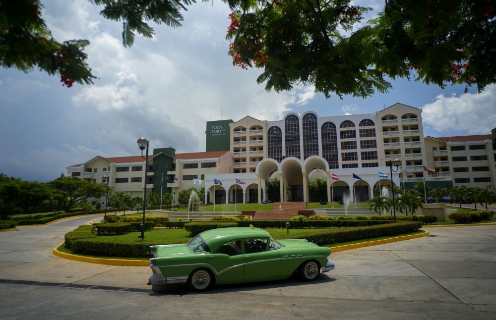 A vintage car passes in front of the Four Points by Sheraton hotel in Havana, Cuba. American hotel giant Starwood has begun managing this hotel owned by the Cuban military.