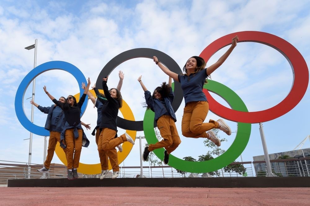 People jump for a picture in front of Olympic Rings set at the Olympic parc in Rio de Janeiro.