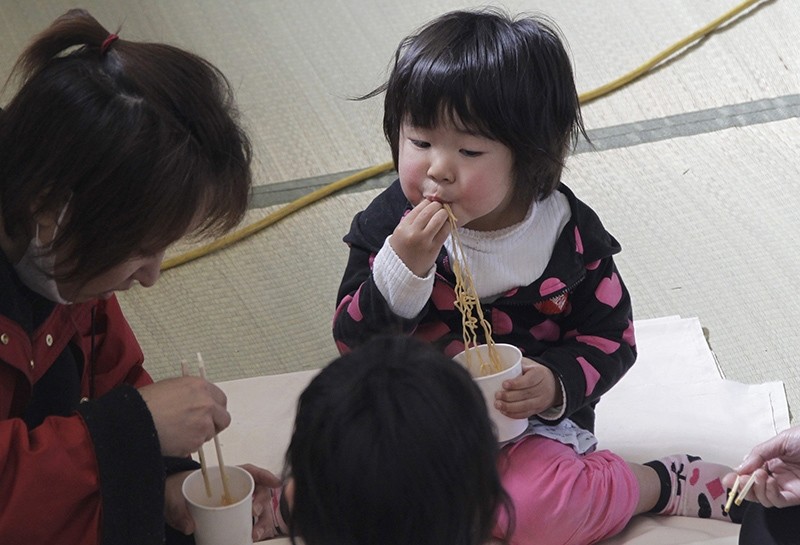 A child eats noodle during a lunch at an evacuation center in Ofunato, Iwate Prefecture, Japan, Sunday, March 20, 2011 (AP Photo)