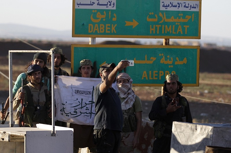 Rebel fighters take a selfie near a road sign in Dabiq town, northern Aleppo countryside, Syria October 16, 2016 (Reuters Photo)