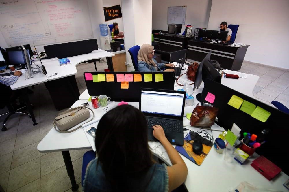 Palestinians work at the office of Red Crow, a startup that monitors security developments and sends real-time alerts and maps to clients, in Ramallah.